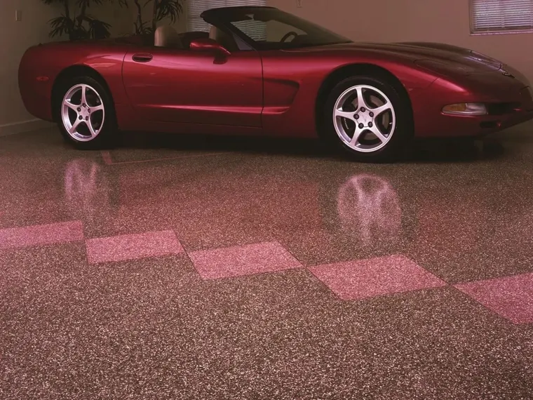 A sports car parked on a flake garage floor with a checkerboard inlay
