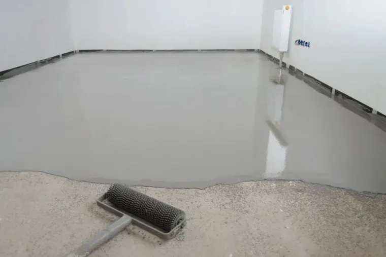 A roller laying a fresh coat over a prepared concrete floor