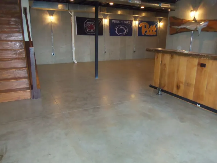 Stained and sealed concrete floor in a finished basement with a wooden bar